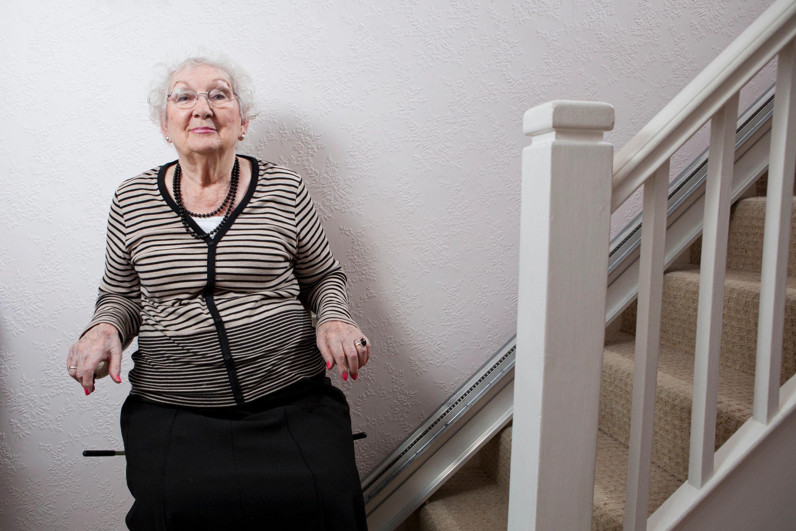 Senior woman riding a curved stair lift